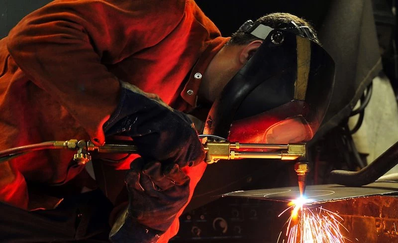 Sailor arc-welds a flange aboard USS Pearl Harbor.