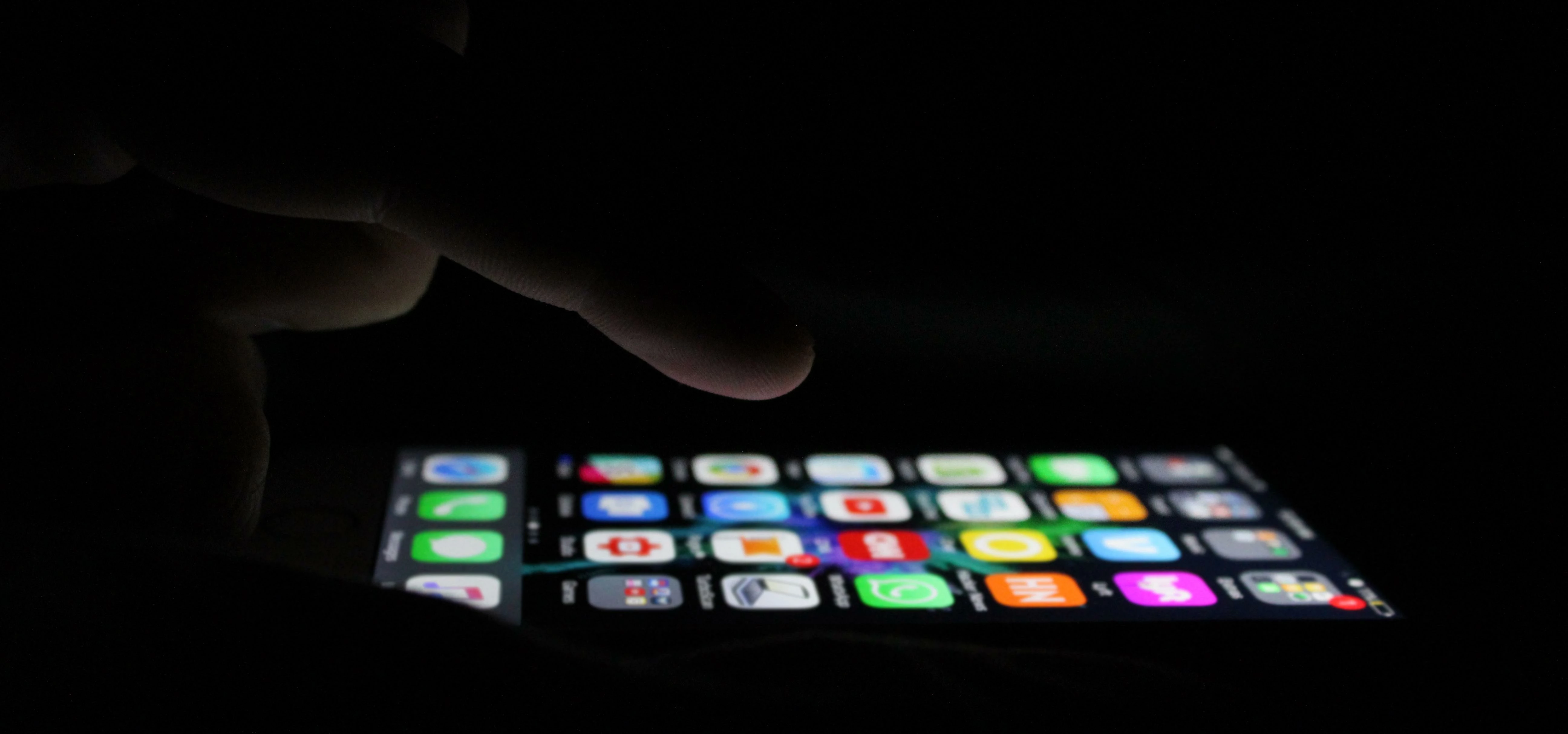 iPhone being touched at night screen illuminated background