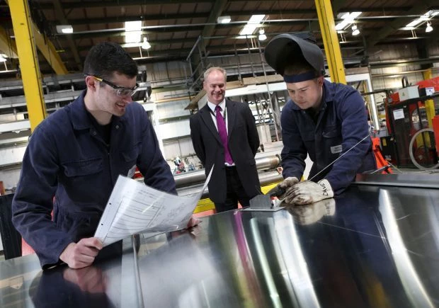 Project Manager Stuart Howson watches apprentices David Pitts and Thomas Murdoch (black hair) in the