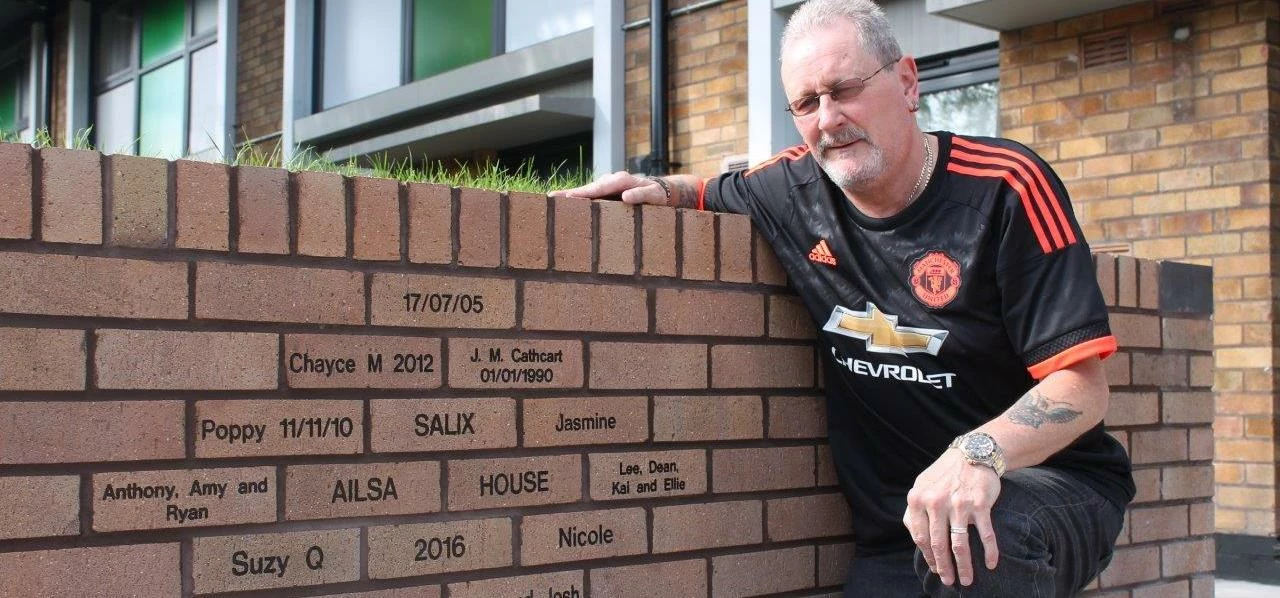 Resident Francis McNulty alongside the engraved bricks at Ailsa House, which includes one in memory 