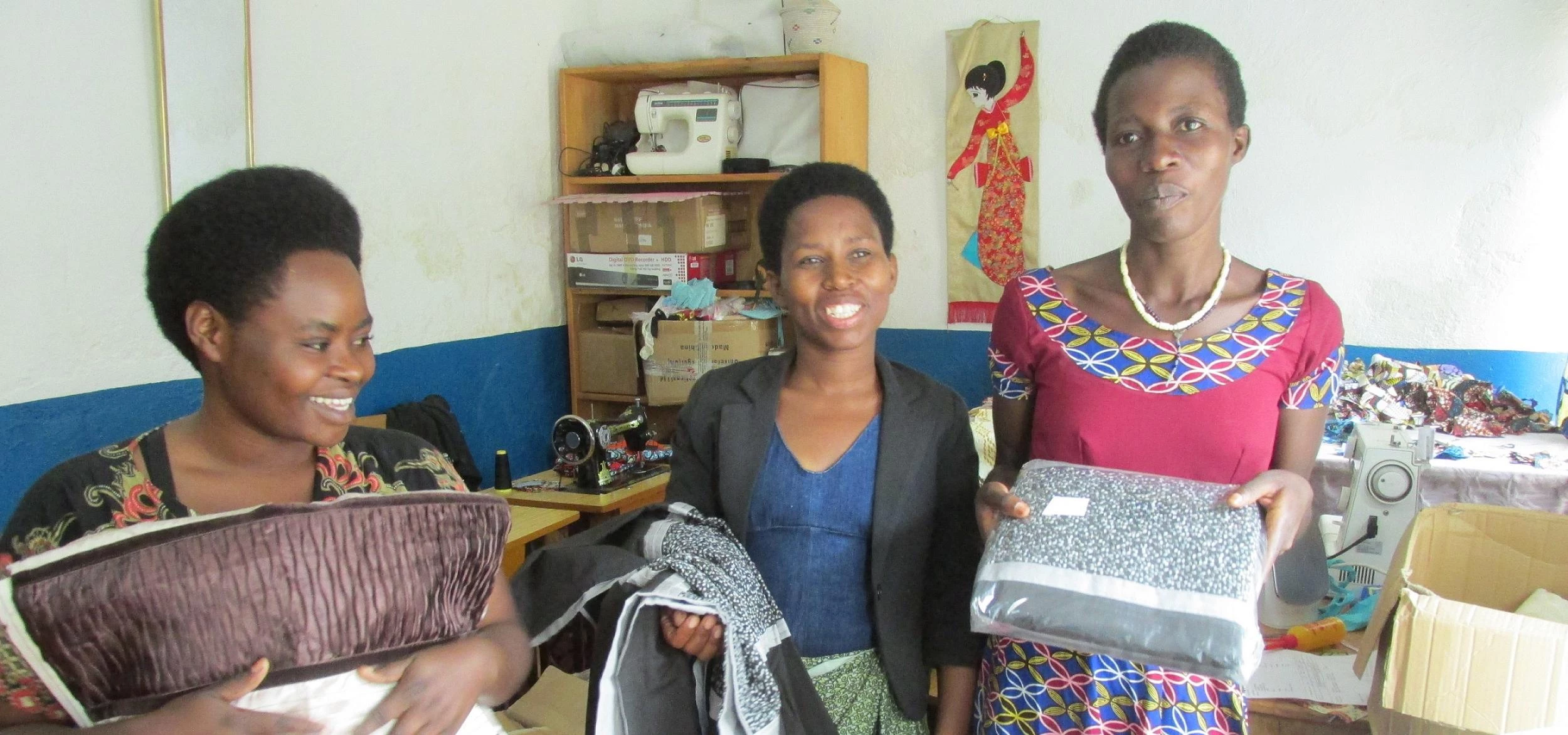 Agnes, Olive and Amina with the fabric donated by SMD Group to their sewing shop in Rwanda