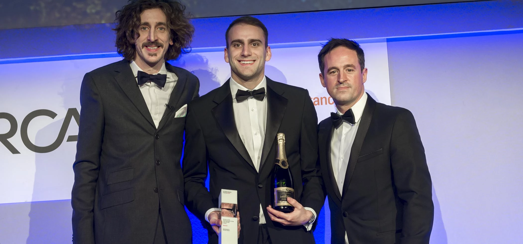 Mechan's Adam Elliott (centre) receives the firm's Rail Industry Award from host and comedian, Tom W