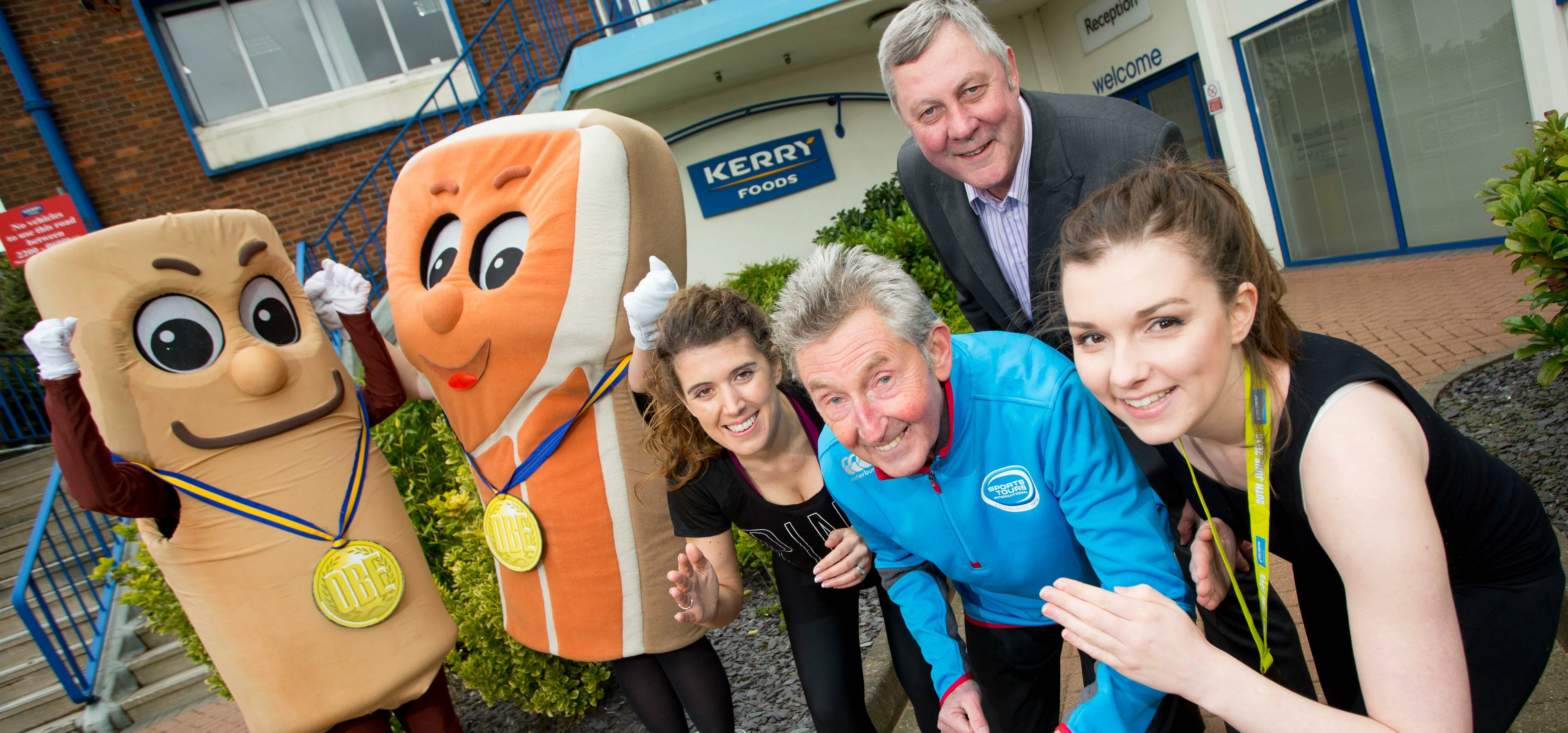 Kerry Foods mascots Sammy Sausage and Ronnie Rasher pose with staff, running legend Ron Hill MBE and