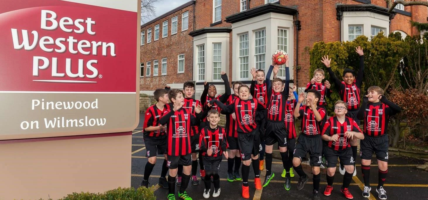 Hazel Grove United Junior FC celebrate in front of Best Western Plus Pinewood on Wilmslow Hotel