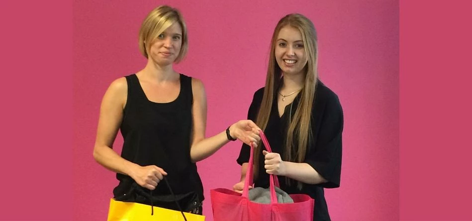 Katy Leeson of Media Com North hands over donated clothes to Georgia Walkden of Smart Works Manchest