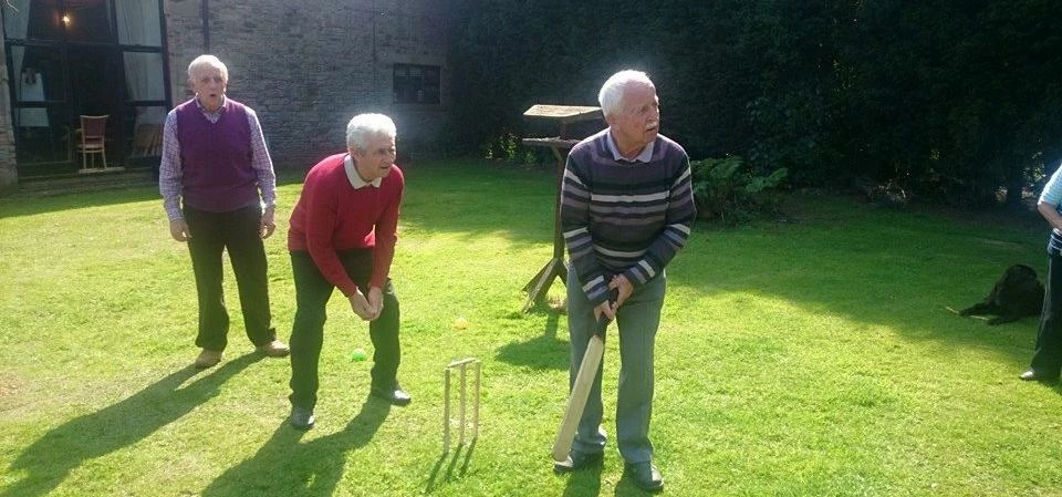 Some service users enjoying a game of cricket in the gardens at Reflections Wigan CIC