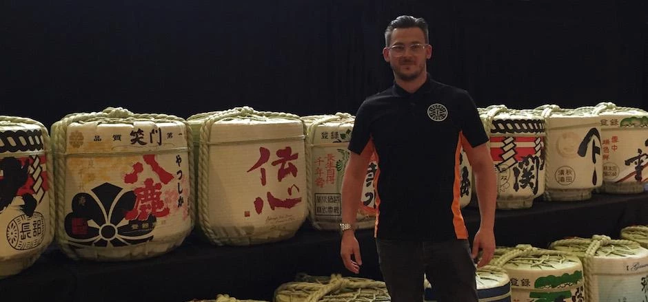 Stuart Turner stood with barrels used in the sake making process.