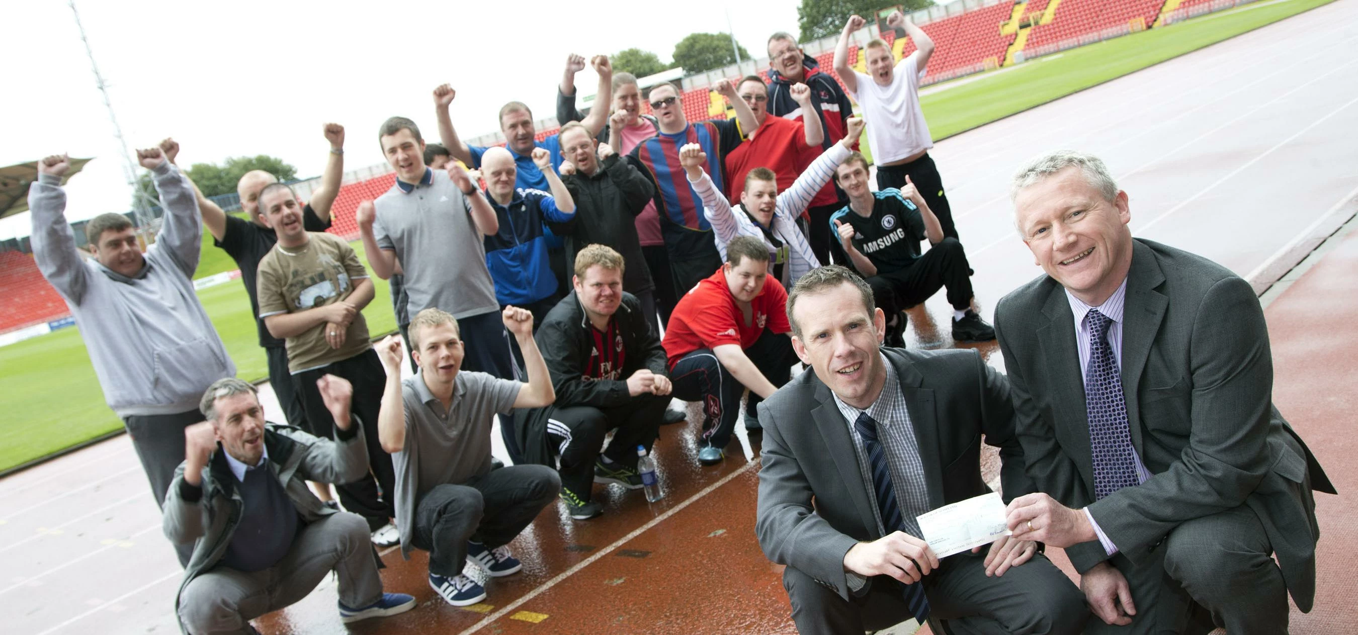 Barry McDonald (Front right) hands the cheque to Keith Hogan as the Gateshead athletes look on.