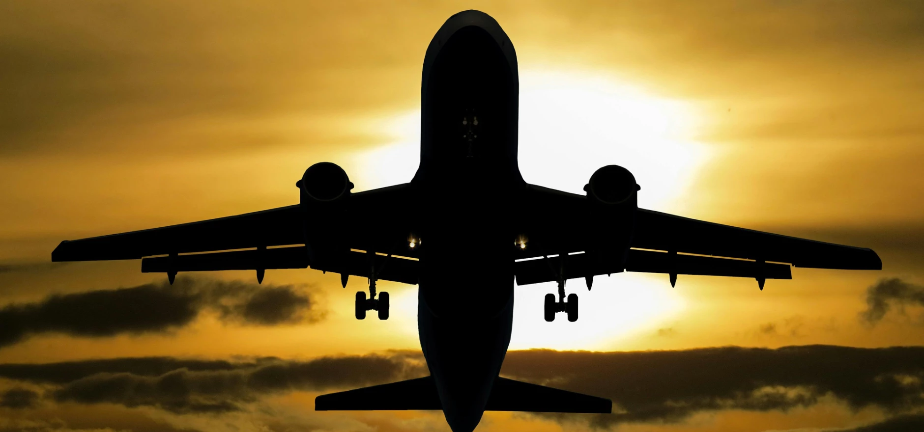 Silhouette of an airplane flying against a dramatic sunset sky.