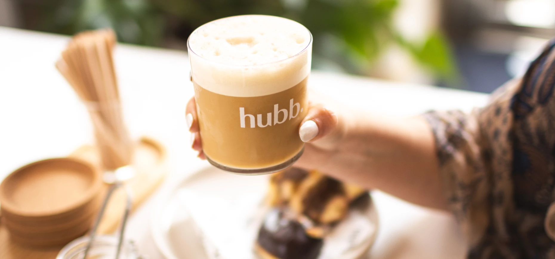 A woman's hand holds a cup of hubb nitro coffee.