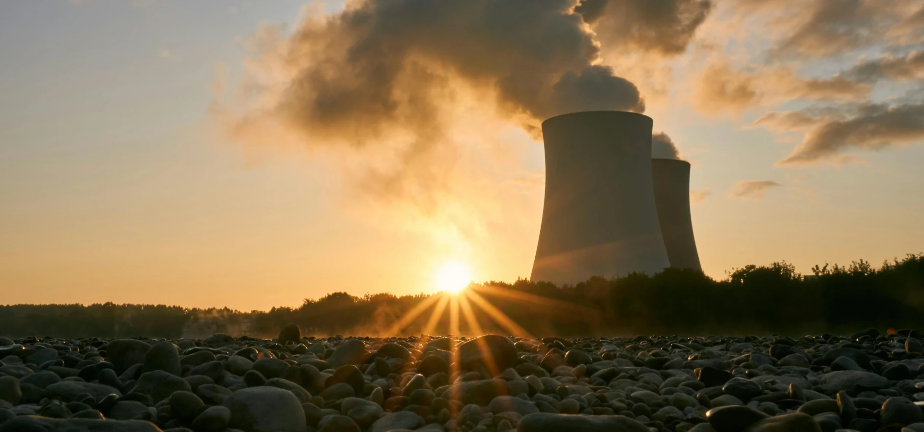 A nuclear power plant emitting steam at sunrise, creating a dramatic skyline with visible air pollution.