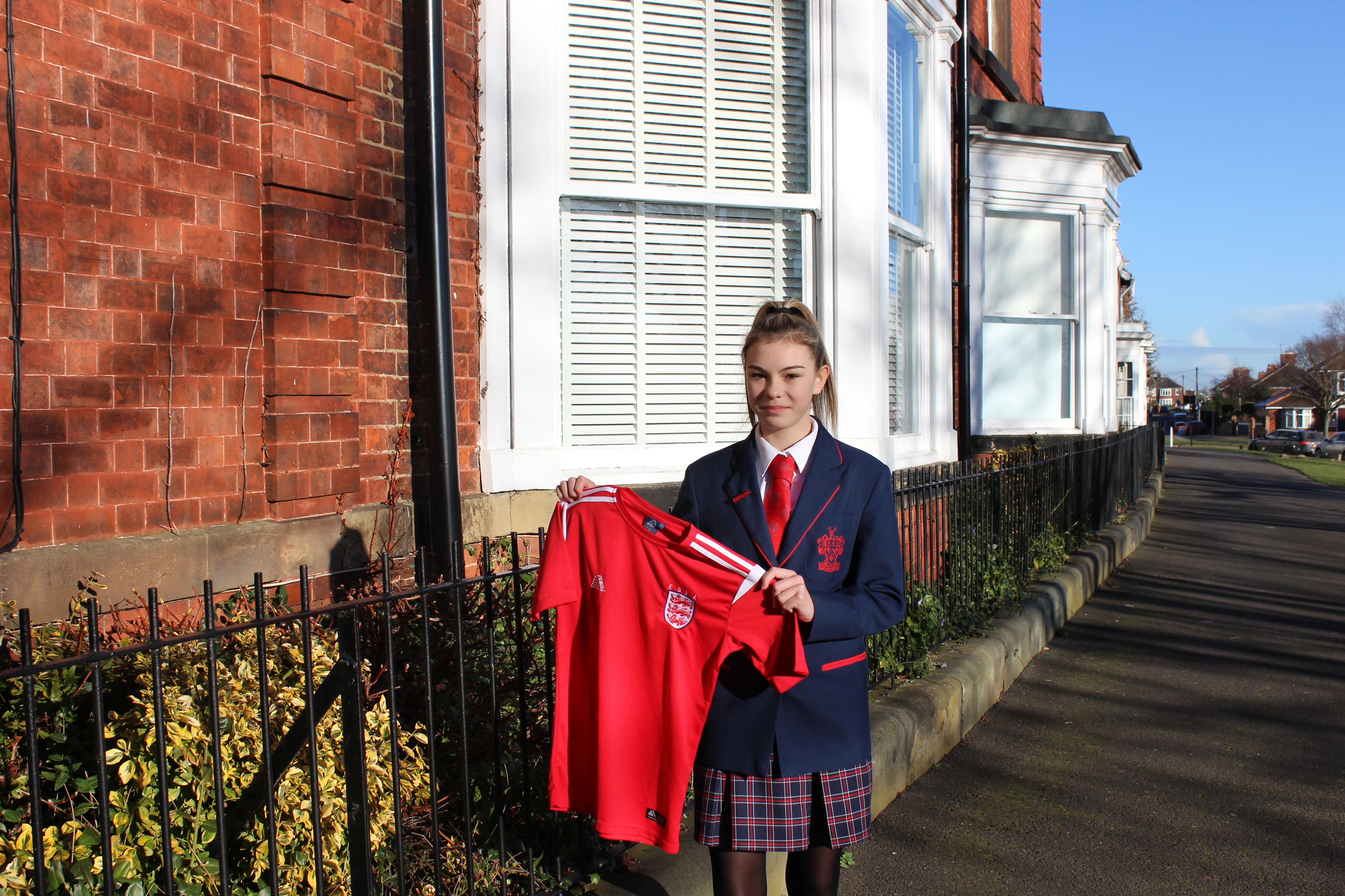 Lily Patrick outside of Red House School, holding her England shirt