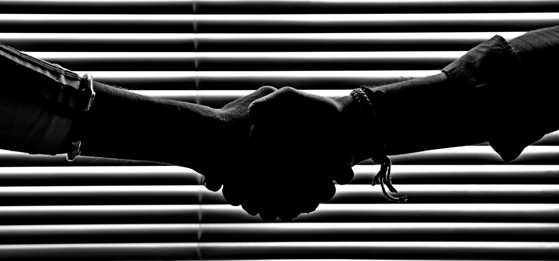 Silhouette of two people shaking hands symbolizing partnership and trust.