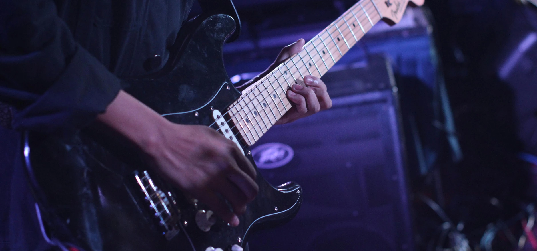 Musician playing an electric guitar on stage during a live performance.