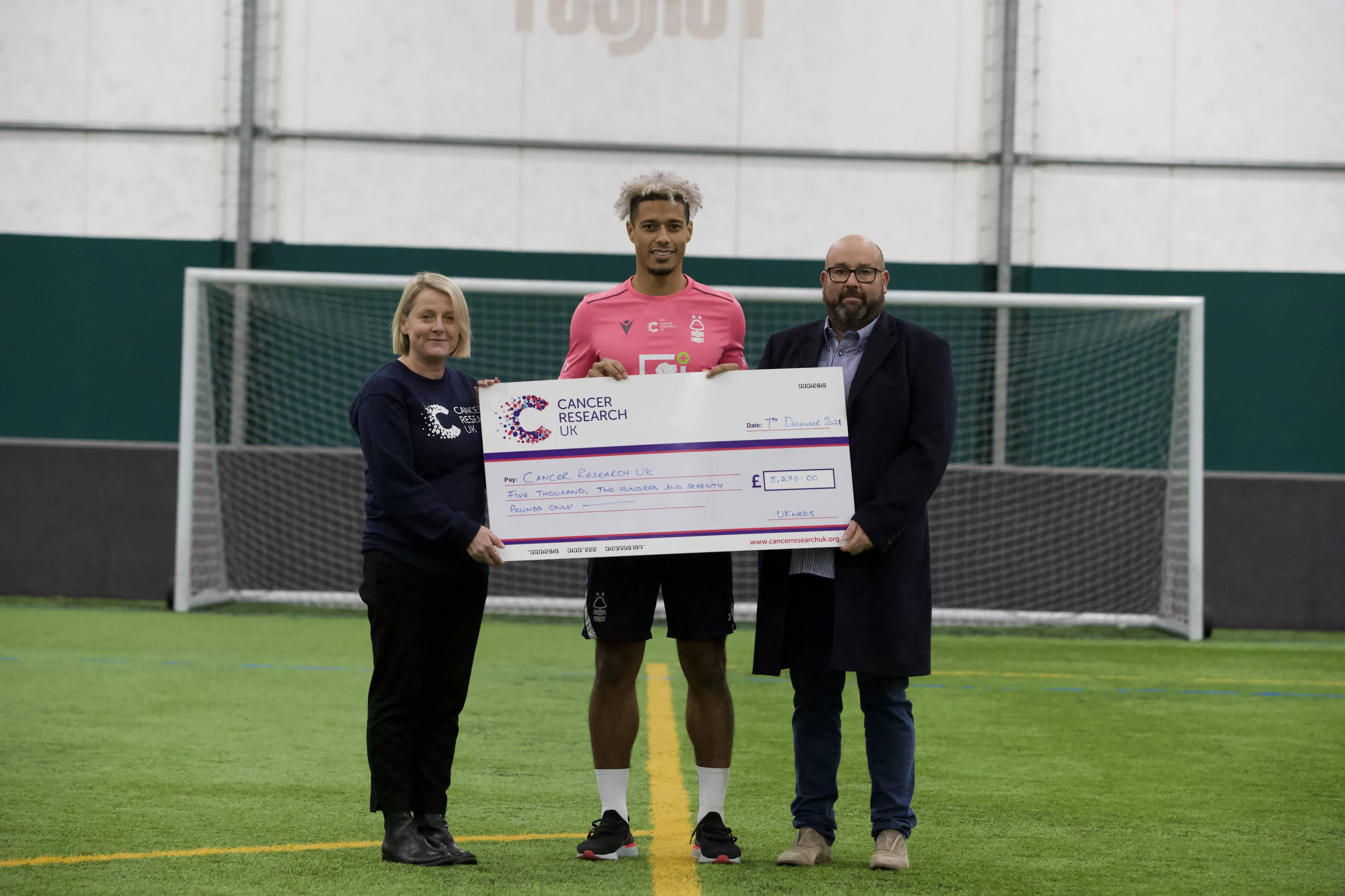 Lyle Taylor (centre) and Joe Soiza from UK Meds present a cheque to Becky Elphick from Cancer Research UK