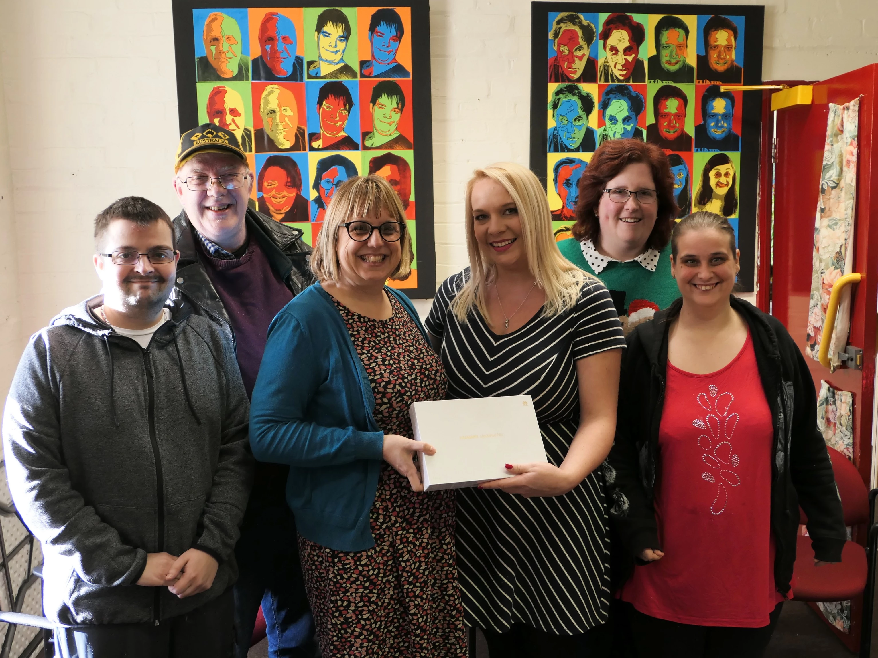 Emma Harris (left) and Helen Eckersall (right) holding the tablet with members of The Hut.