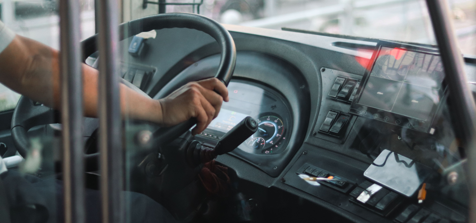Close-up of a bus driver controlling the steering wheel in a bustling city environment.