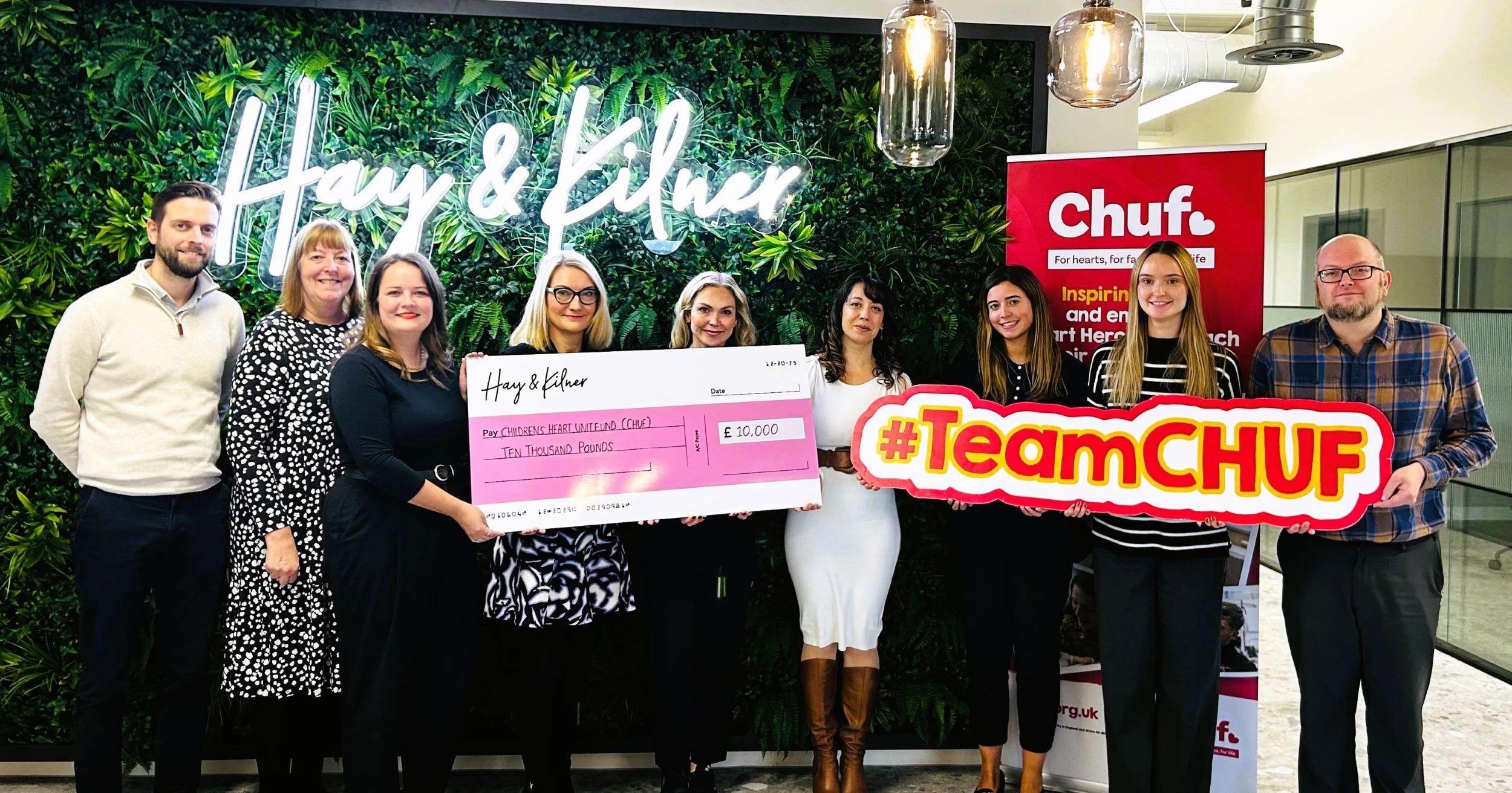 Members of the Hay & Kilner team presenting a cheque for £10,000 to (centre, white dress) Alicia Clovis-Mothalib, corporate & trusts fundraising manager at Chuf