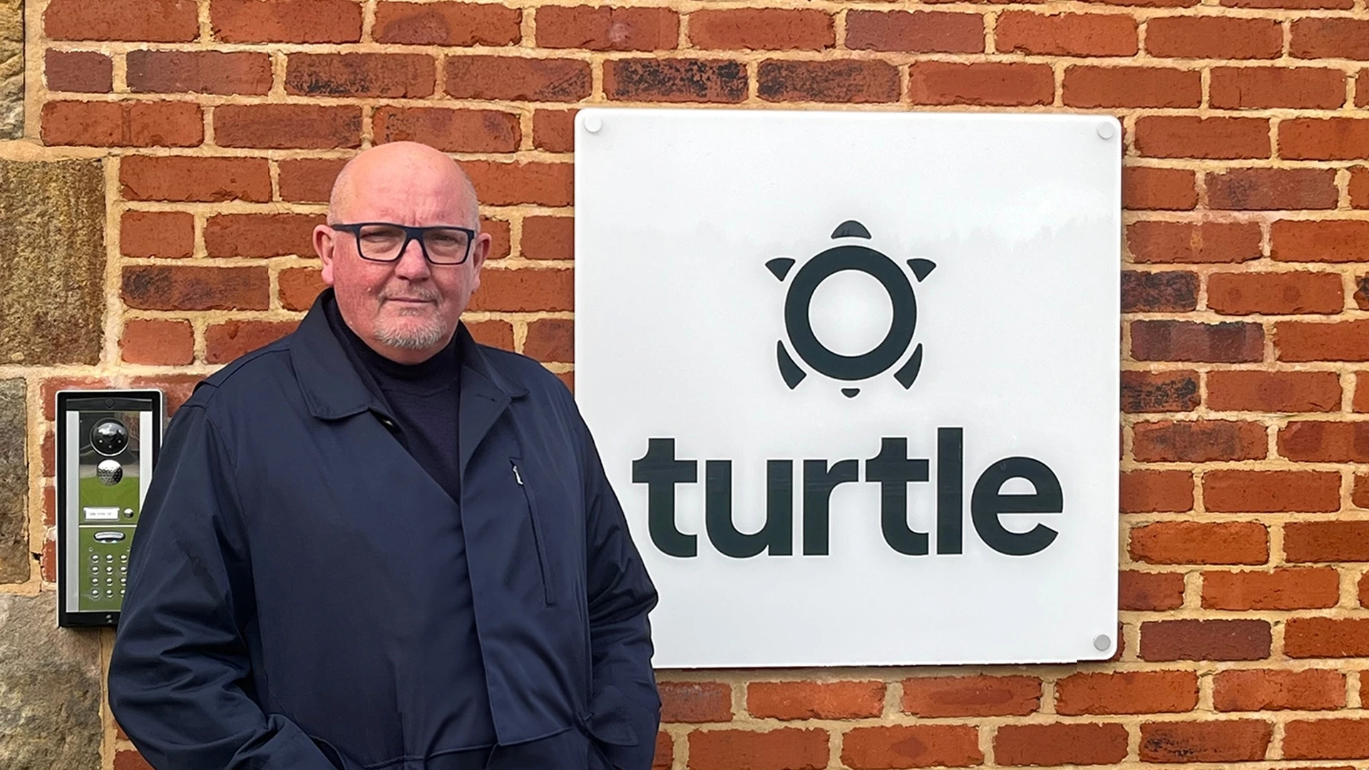Managing Director, Damone Armstrong in front of Turtle Enviro Logo