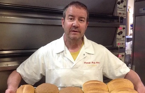 Dave Longstaff with some of the loaves of bread being baked for The Auckland Project; Closed Doors, Open Hearts.  Photo courtesy of Longstaff’s Family Bakers and Coffee Shop. 