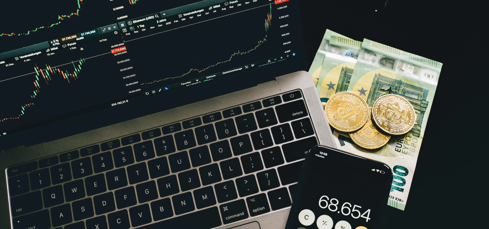 A laptop displaying stock charts with Bitcoin, Euros, and a cellphone calculator, showcasing financial analysis.