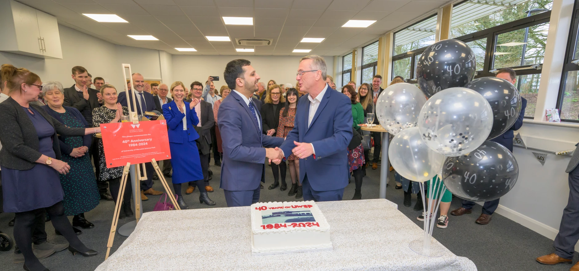Saqib Bhatti MP, Minister for Tech and the Digital Economy (left), shaking hands with Stuart Croft, Vice Chancellor of the University of Warwick, after a ceremonial cutting of cake to mark the University of Warwick Science Park’s 40th anniversary