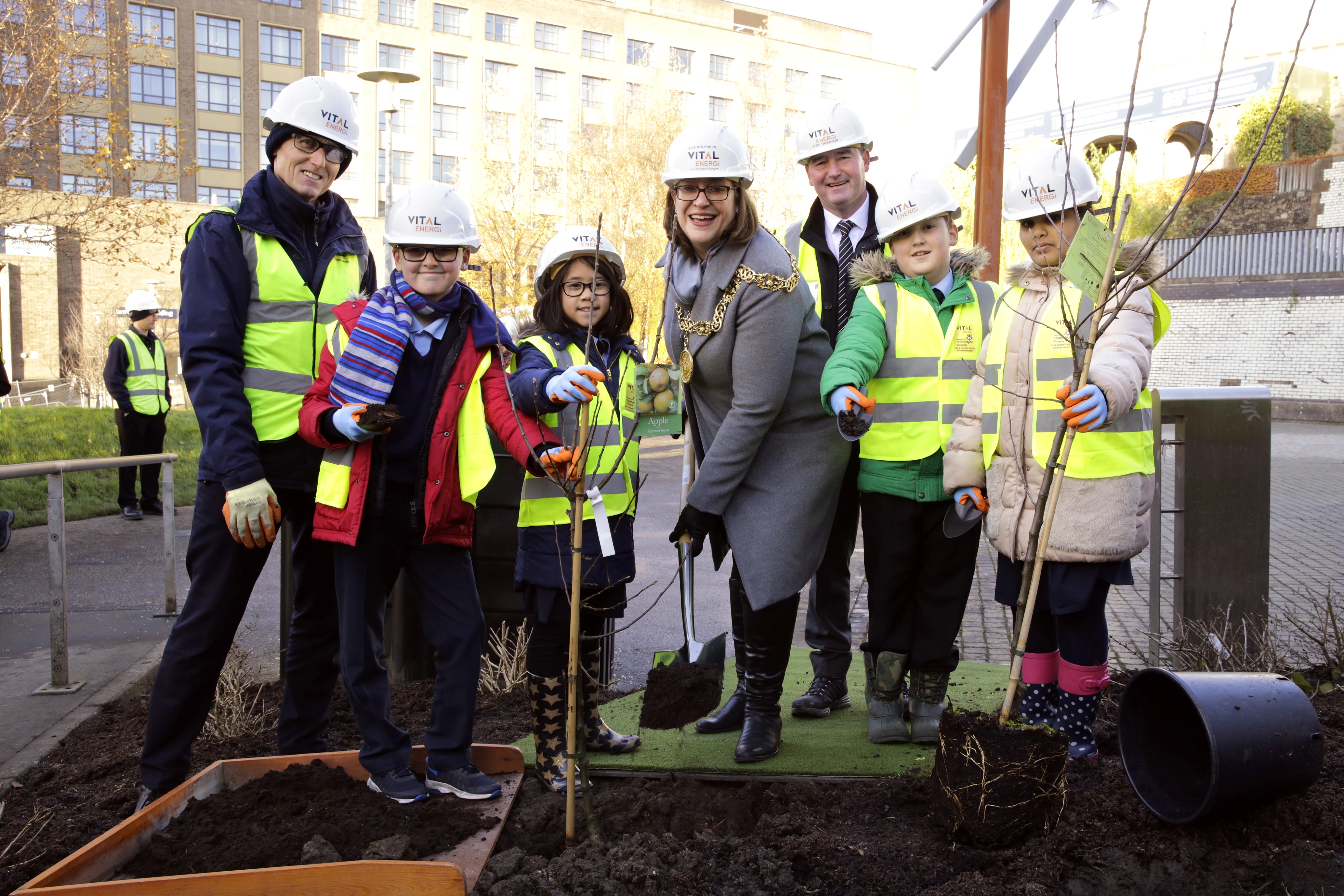 Roddy Yarr, Assistant Director of Estates Services at the University of Strathclyde (Left), Glasgow Lord Provost Eva Bolander (Centre) Hugh Thompson, Project Director for Vital Energi (Right) joined by pupils from St Mungo’s Primary