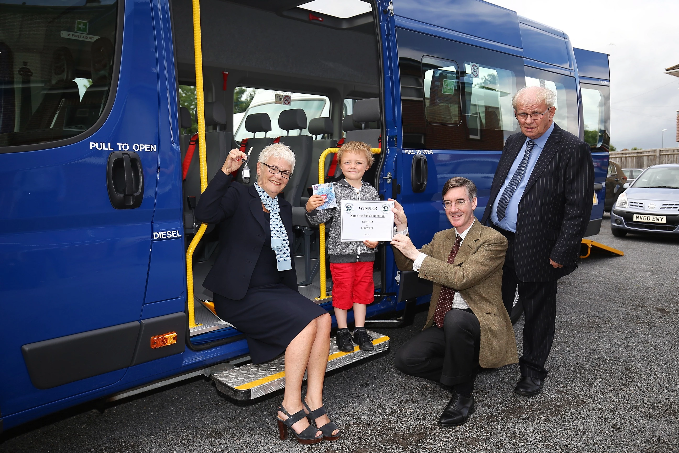 Barratt and David Wilson Homes sales adviser Kirstie Brown handing keys to the new bus over to Keynsham Dial a Ride, Cllr Brian Simmons, MP Jacob Rees-Mogg and competition winner Leo Watt aged 5 who named the bus.