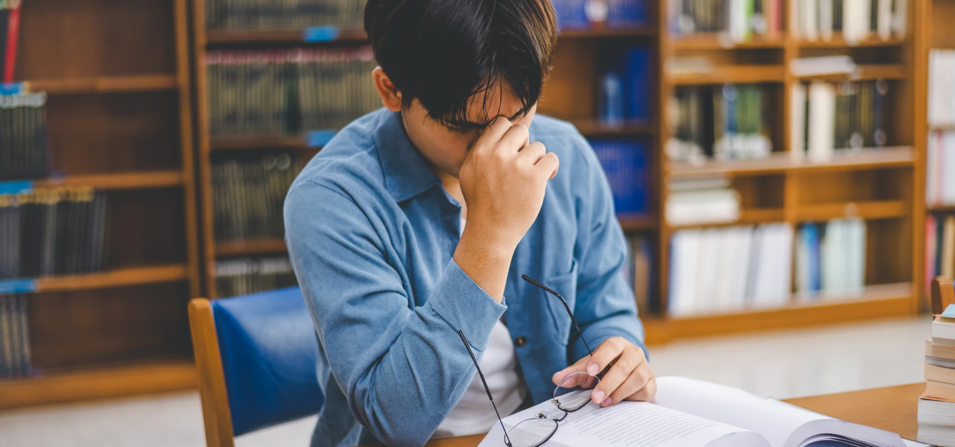Students feel tired and stressed after working on their laptops and looking for books