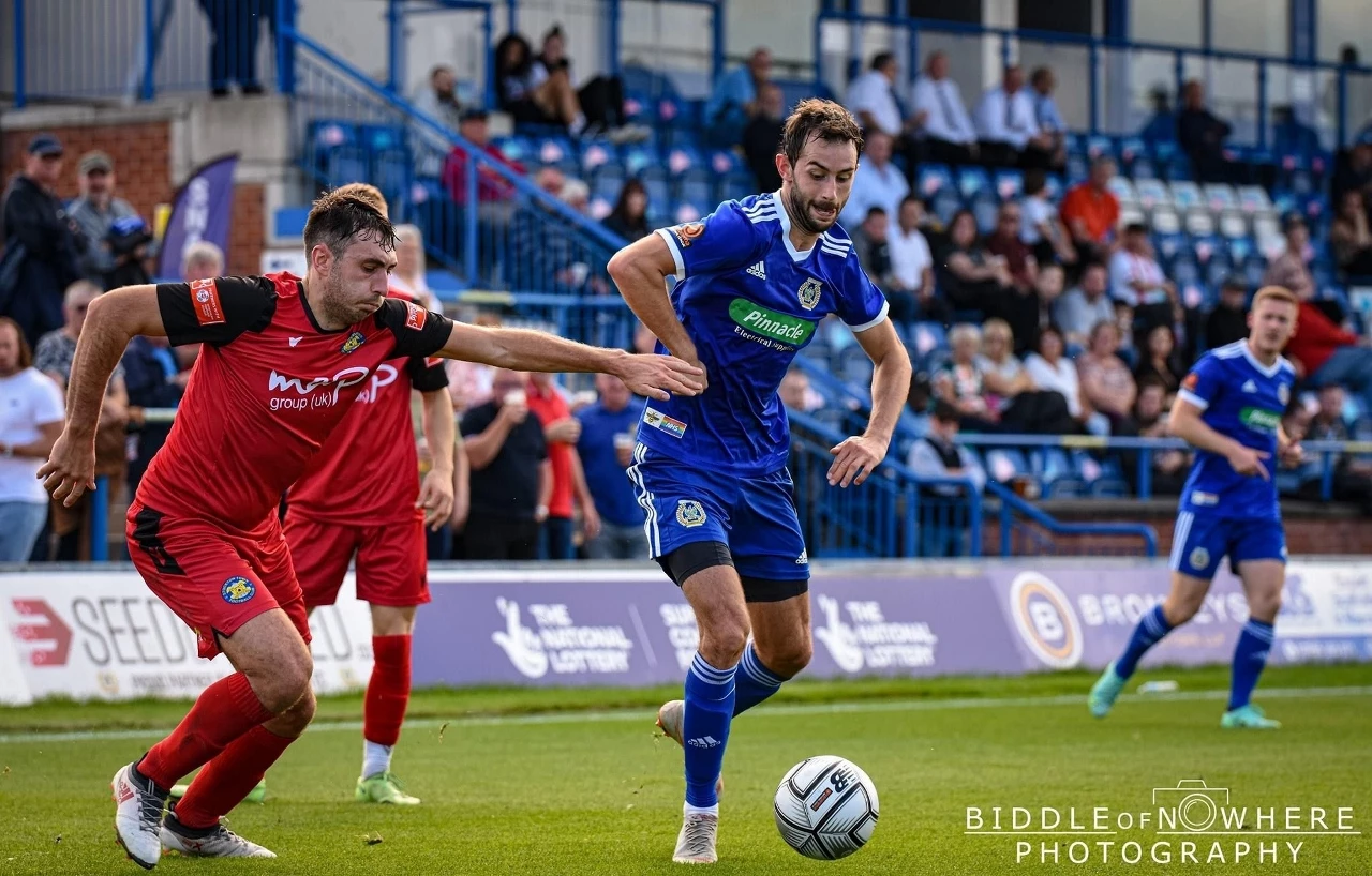 Curzon Ashton midfielder Adam Thomas (blue kit) in action against Darlington earlier this season. Image courtesy of Biddle of Nowhere Photography.